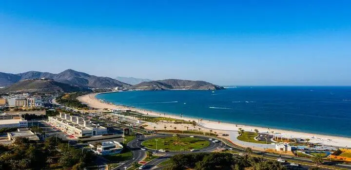Khorfakkan Beach in Sharjah, UAE with clear waters, sandy shore, and Hajar Mountains in the background